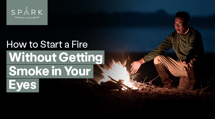 Person lighting a campfire outdoors showing how to start a fire without getting smoke in your eyes