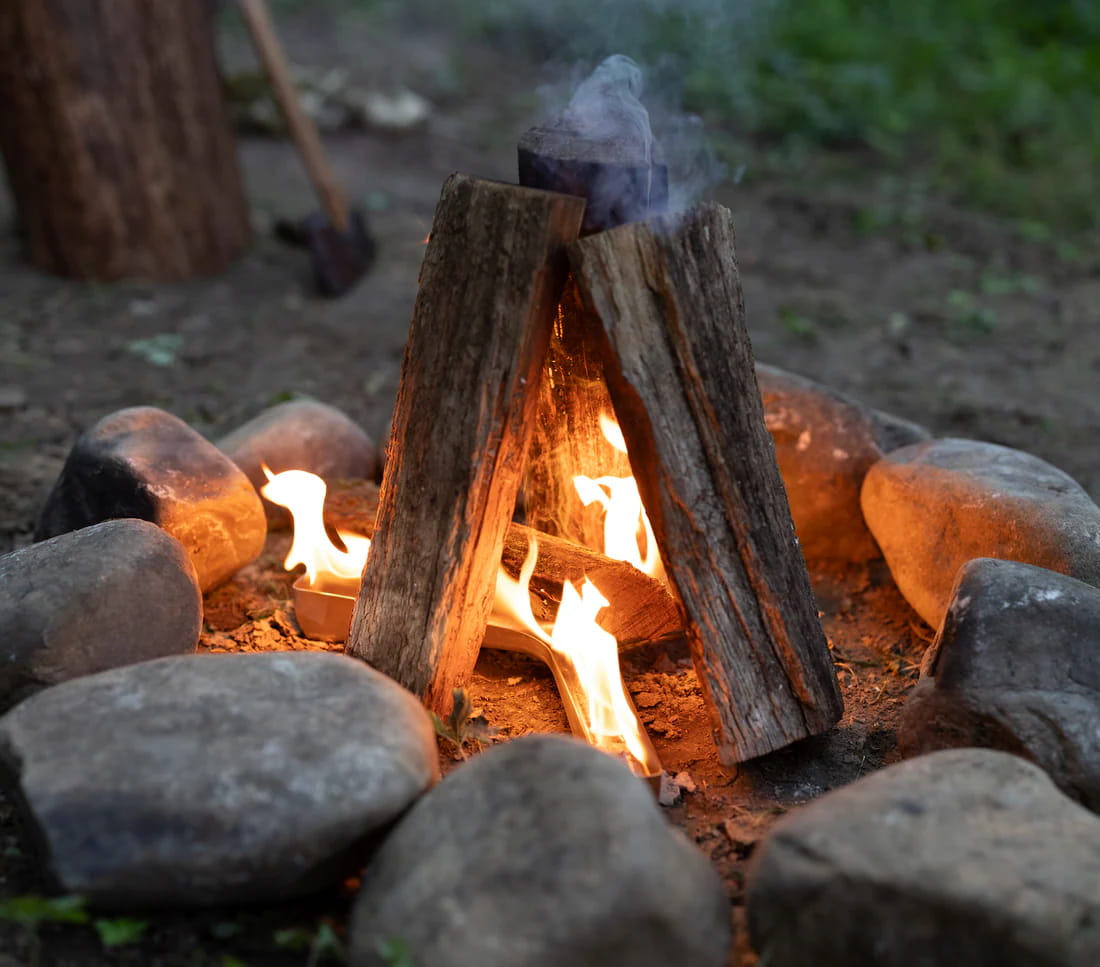 Campfire with stacked logs and bright flames in an outdoor fire pit